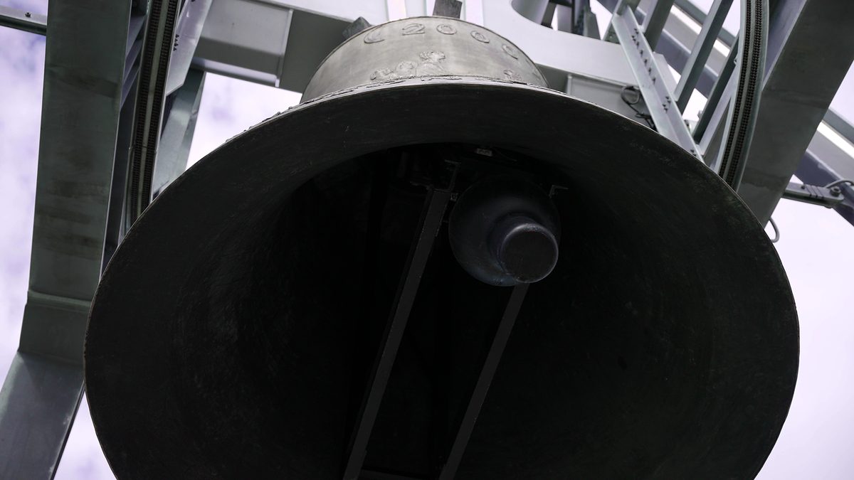 Der Blick von unten in die offene Friedensglocke mit dem schweren Klöppel.
