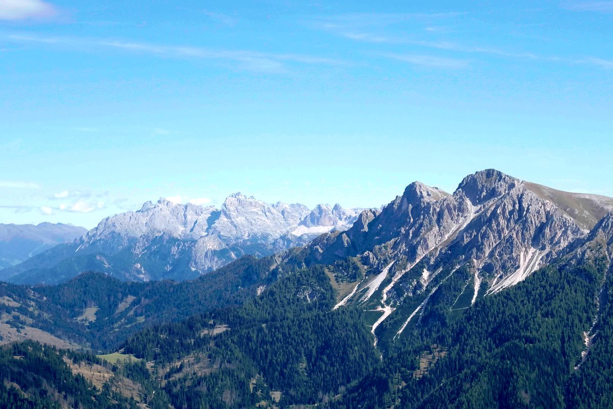 Ein scharfer Bergkamm zieht vor den Dolomiten unter blauem Himmel nach rechts.